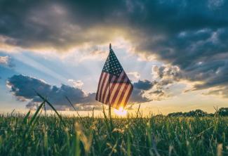 flag of USA on grass field by Aaron Burden courtesy of Unsplash.